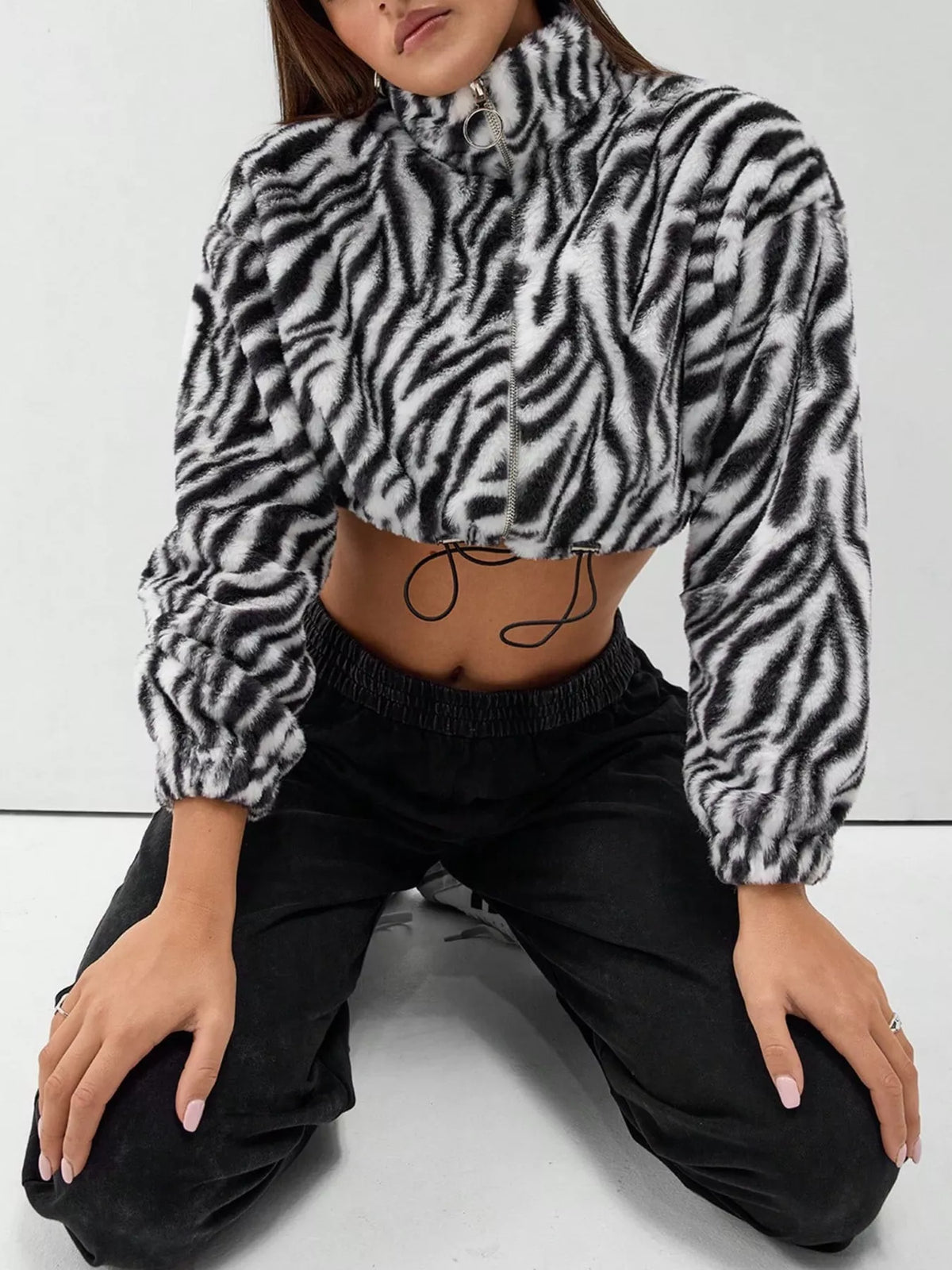 Plush cropped zebra print jacket in black with drawstring closure and zip front.