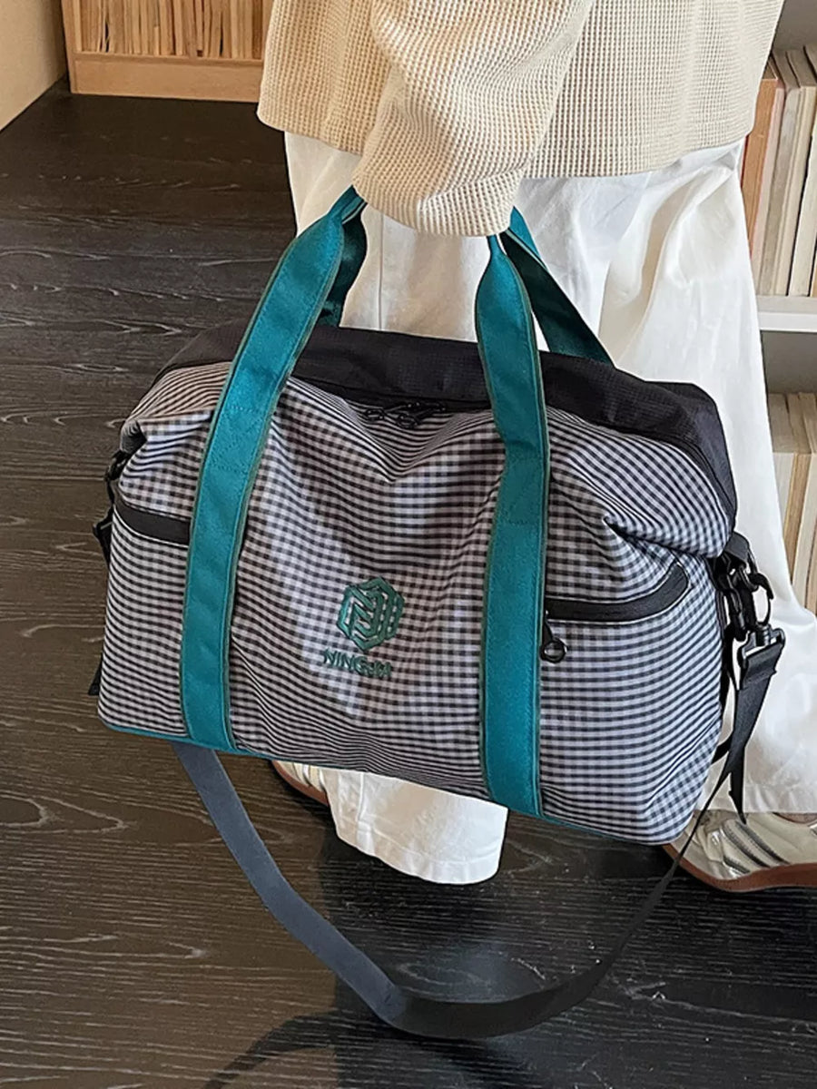 Large plaid travel bag with turquoise straps and versatile carrying options.