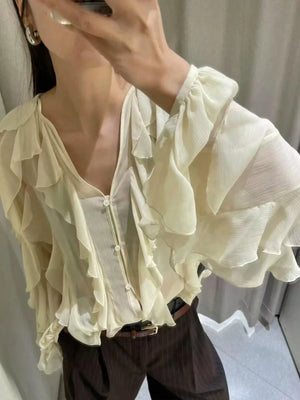 Sheer beige ruffled long-sleeve blouse with V-neck and button front.