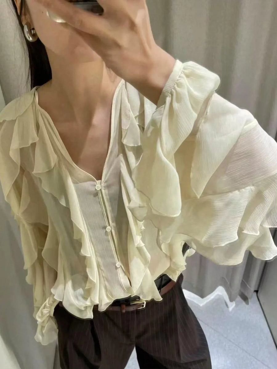 Sheer beige ruffled long-sleeve blouse with V-neck and button front.