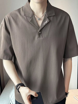 Taupe cotton polo shirt with embroidered detail and button neck.