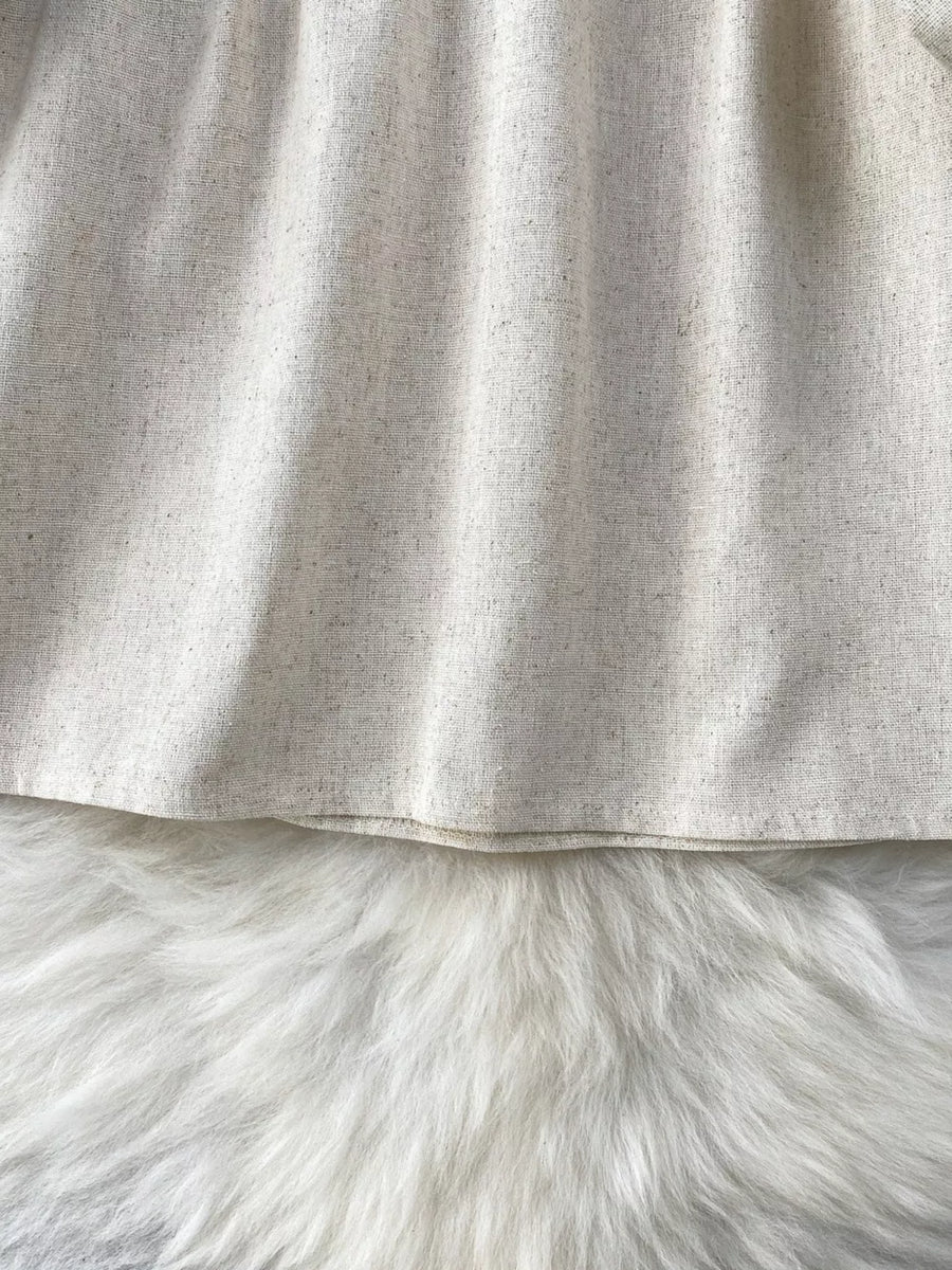 Cream tie-neck blouse with textured fabric and delicate embroidery detail