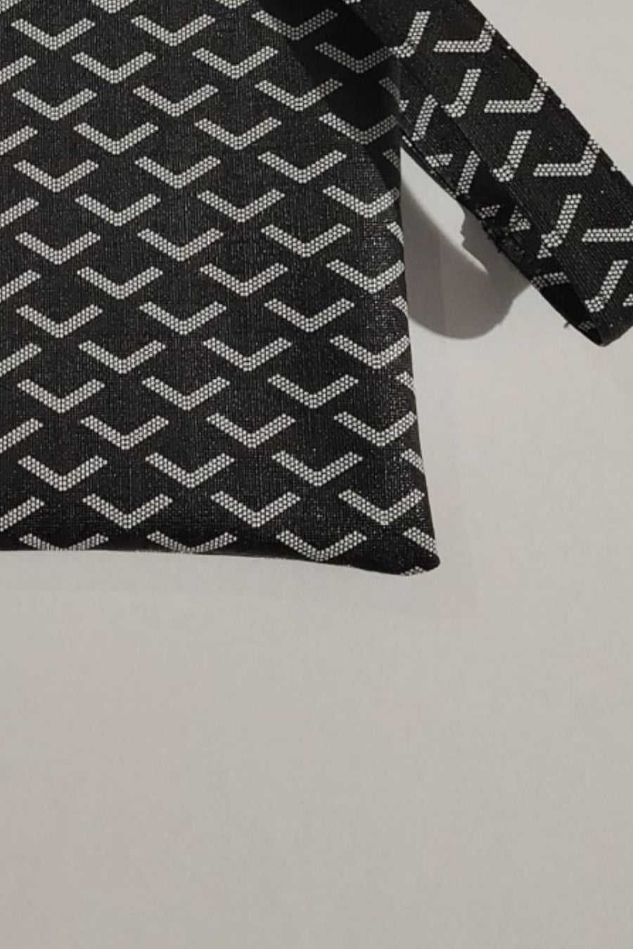 Black clutch bag with geometric pattern and wrist strap detail
