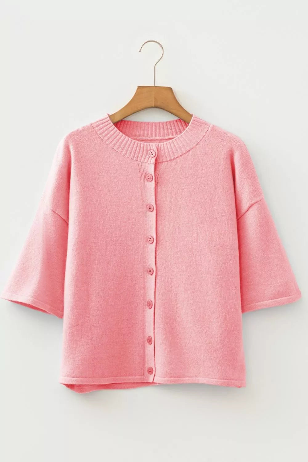 Pink boxy knit cardigan with button front and short sleeves.