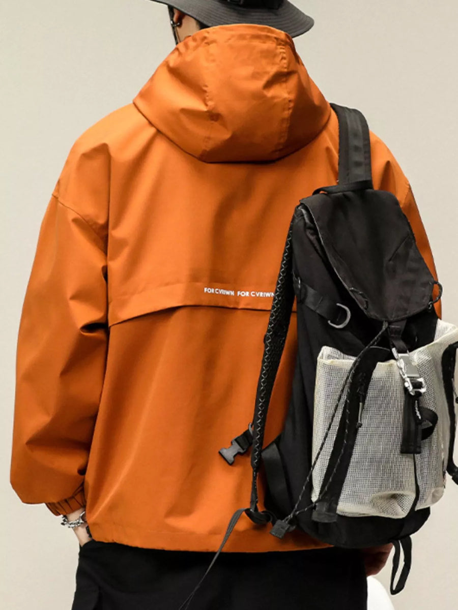 Orange hooded windbreaker jacket with white text detail on back, worn with a backpack.