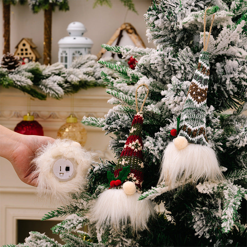Illuminated gnome ornaments with knitted hats and white beards, one held by a hand.