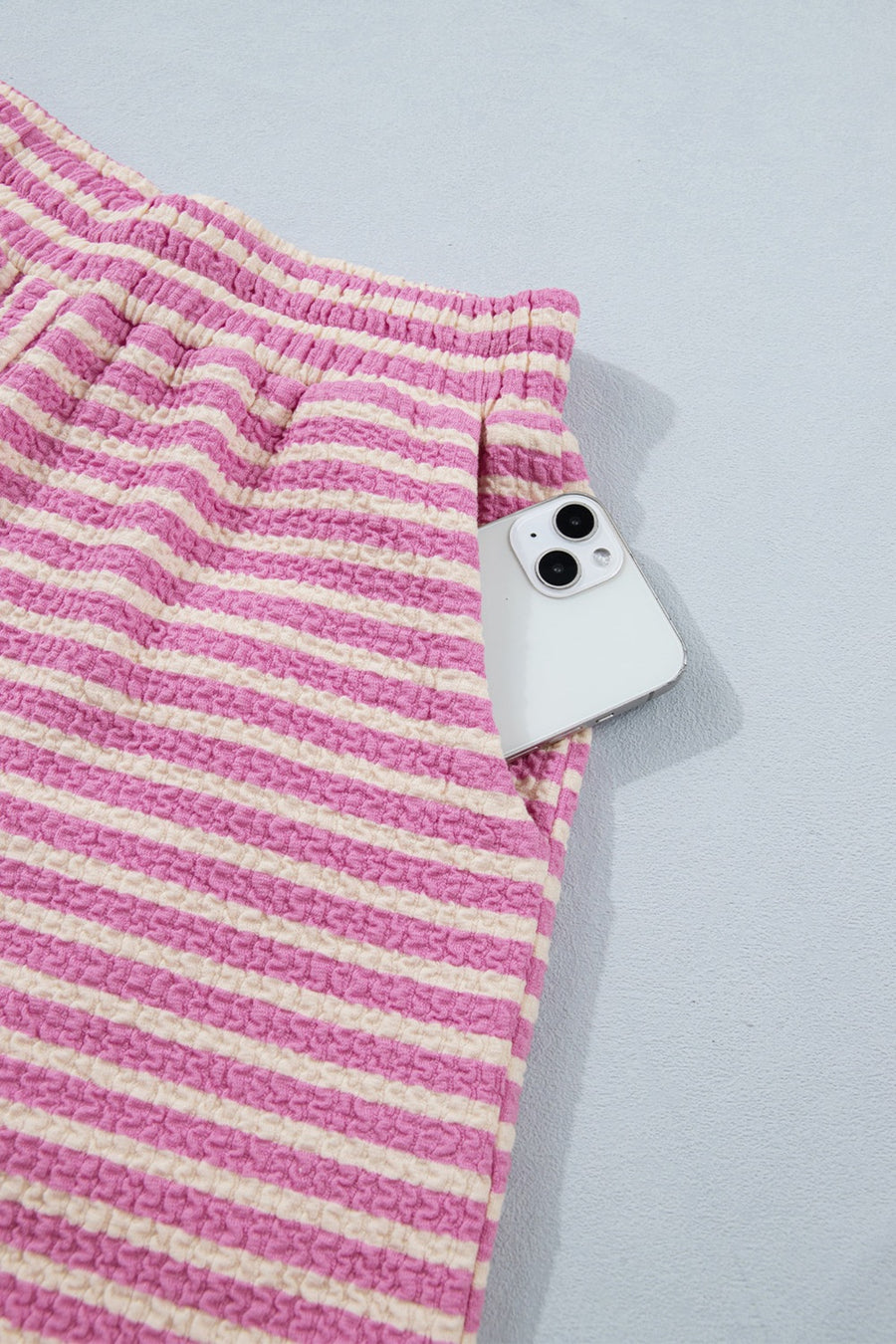 Textured stripe two-piece set with pink and cream horizontal stripes and a phone in the pocket.