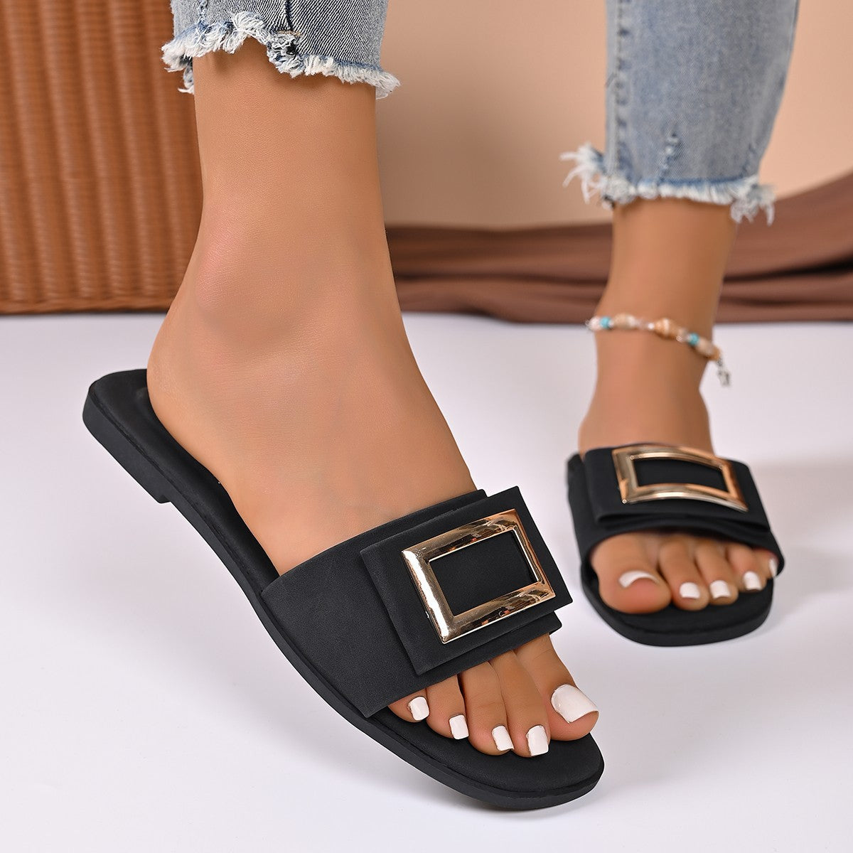Black buckle slide sandals with open toe and gold hardware detail.