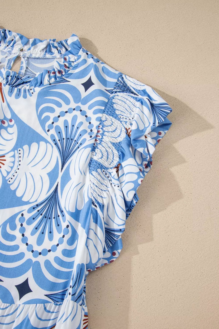 Blue and white botanical print ruffled dress with flutter sleeves and smocked details.