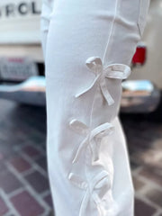 White cotton maternity trousers with bow embellishments on the side seam.