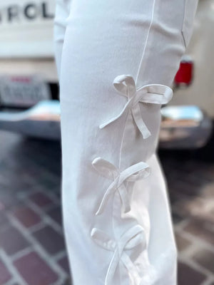White cotton maternity trousers with bow embellishments on the side seam.