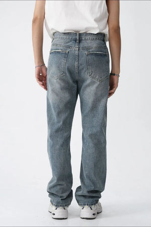 Relaxed fit straight leg jeans in medium wash denim with distressed details.