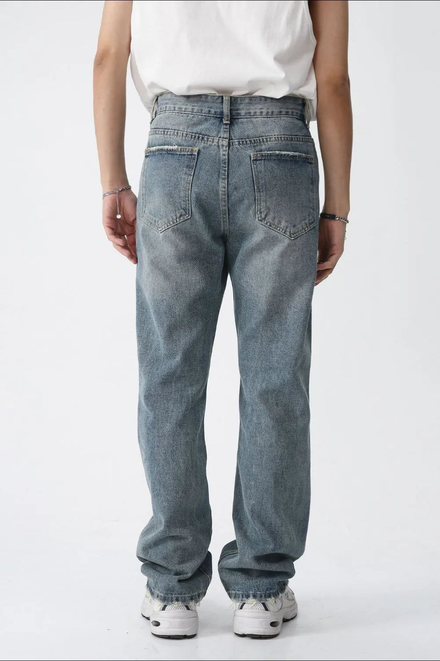 Relaxed fit straight leg jeans in medium wash denim with distressed details.