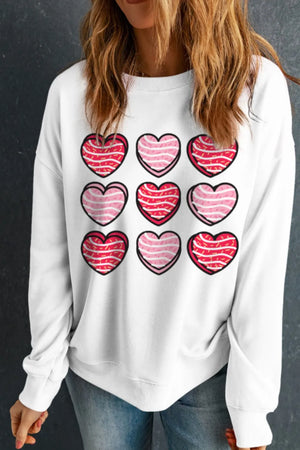 White crewneck sweatshirt with a grid of nine hearts graphic, featuring pink and red stripes.