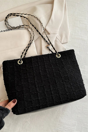 Black bouclé shoulder bag with textured weave and gold chain strap detail