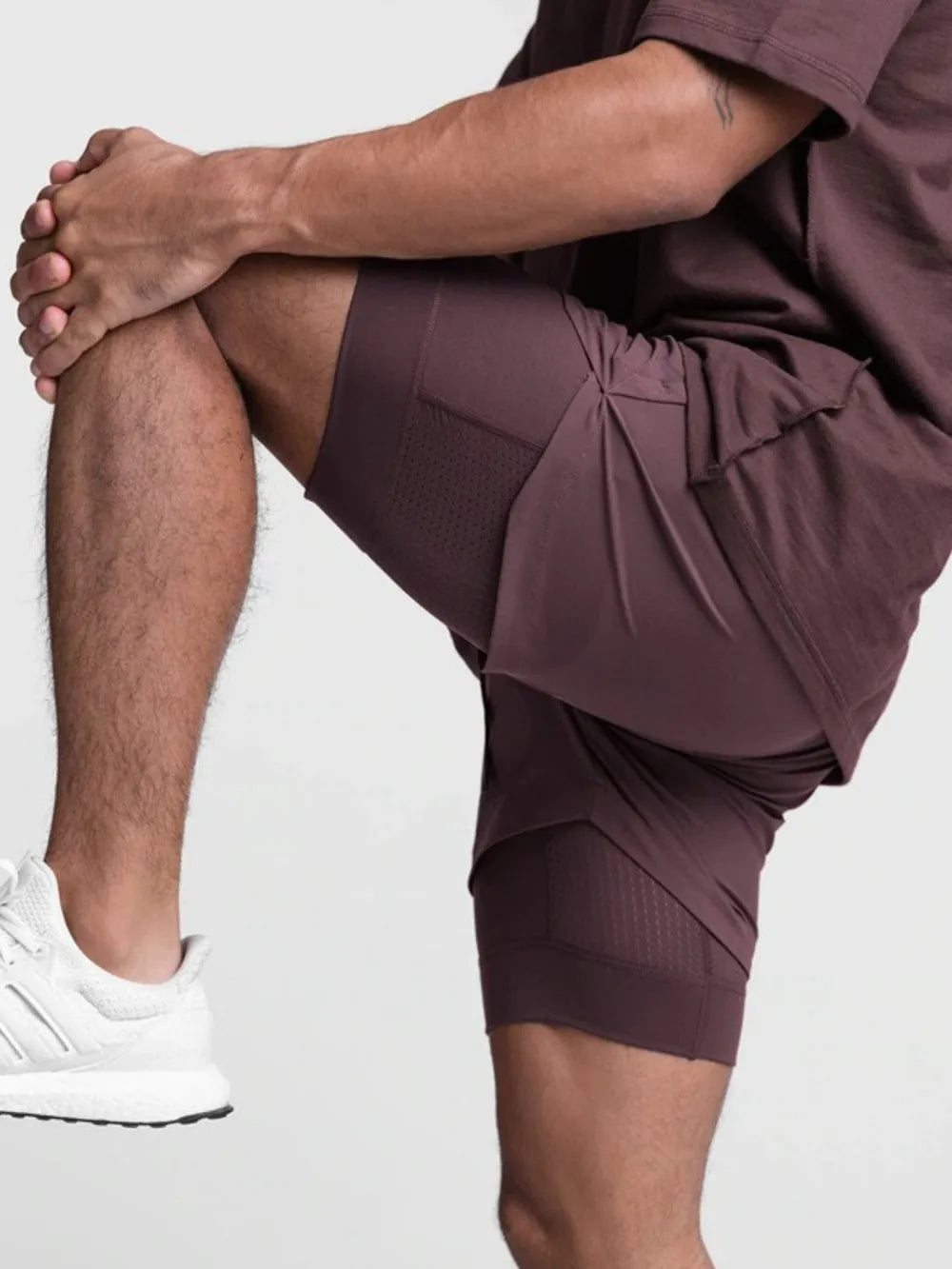 Plum purple layered performance shorts with perforated side panels and a built-in liner.