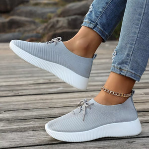 Gray lace-up sneakers with white mid sole and ribbed knit upper.
