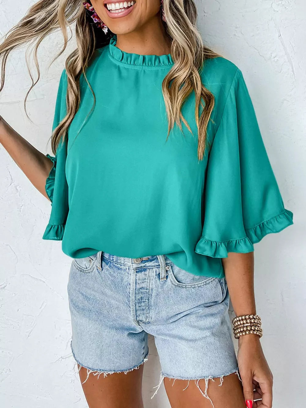 Teal ruffled mock neck half sleeve shirt with ruffled cuffs.