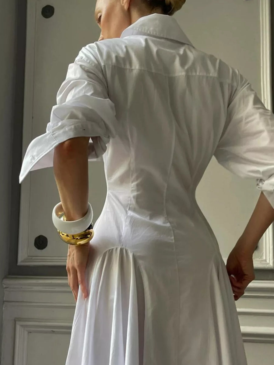 White cotton shirt dress with gathered skirt and rolled sleeves, styled with bold bracelets.