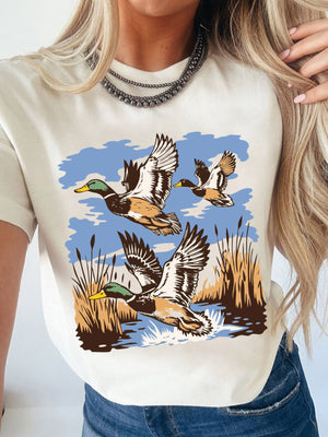 Cream cotton t-shirt with a graphic of three mallard ducks flying over reeds and water.