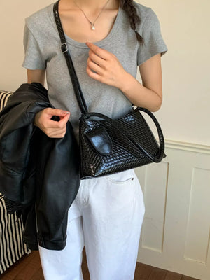 shoulder bag in black featuring woven texture and structured fit