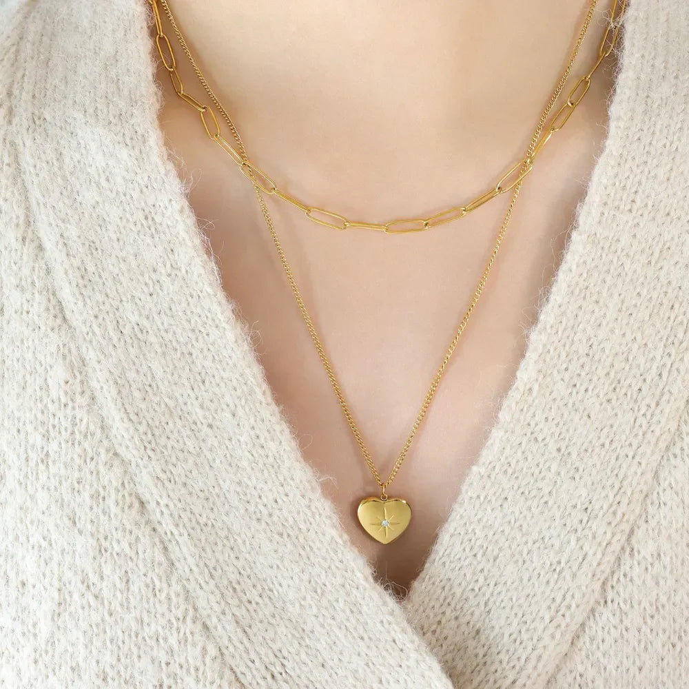 Gold layered necklaces with paperclip chain and heart pendant with starburst detail