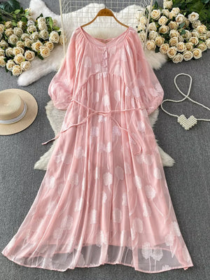 Pink chiffon maxi dress with floral embroidery, V-neck, button-down front, and belted waist.