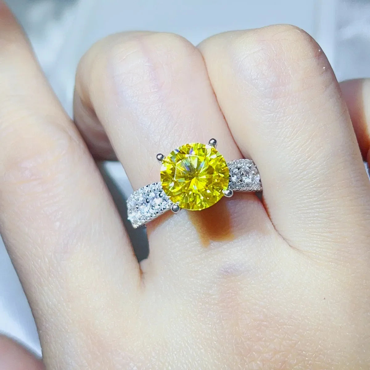 Yellow moissanite ring with pavé band on finger