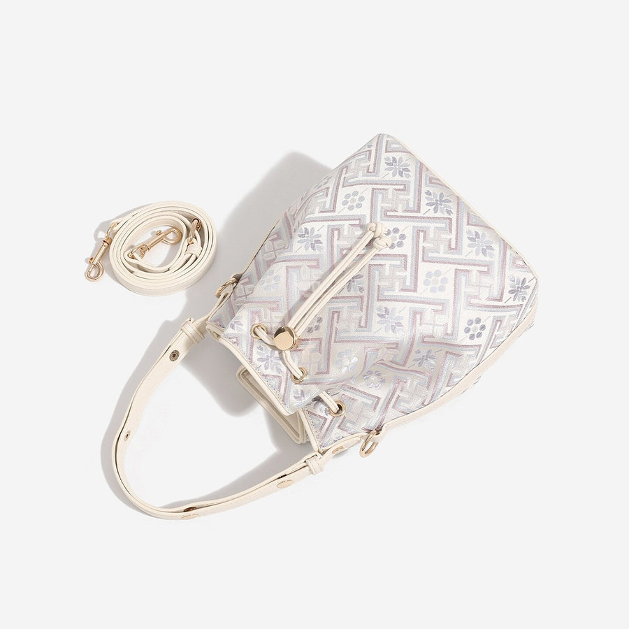 Cream crossbody bag featuring drawstring closure and geometric