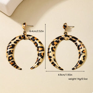 Gold crescent dangle earrings with leopard print pattern.