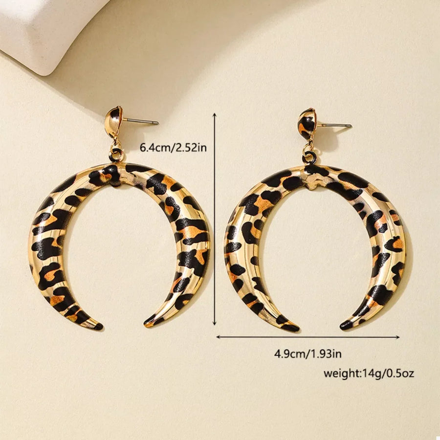 Gold crescent dangle earrings with leopard print pattern.