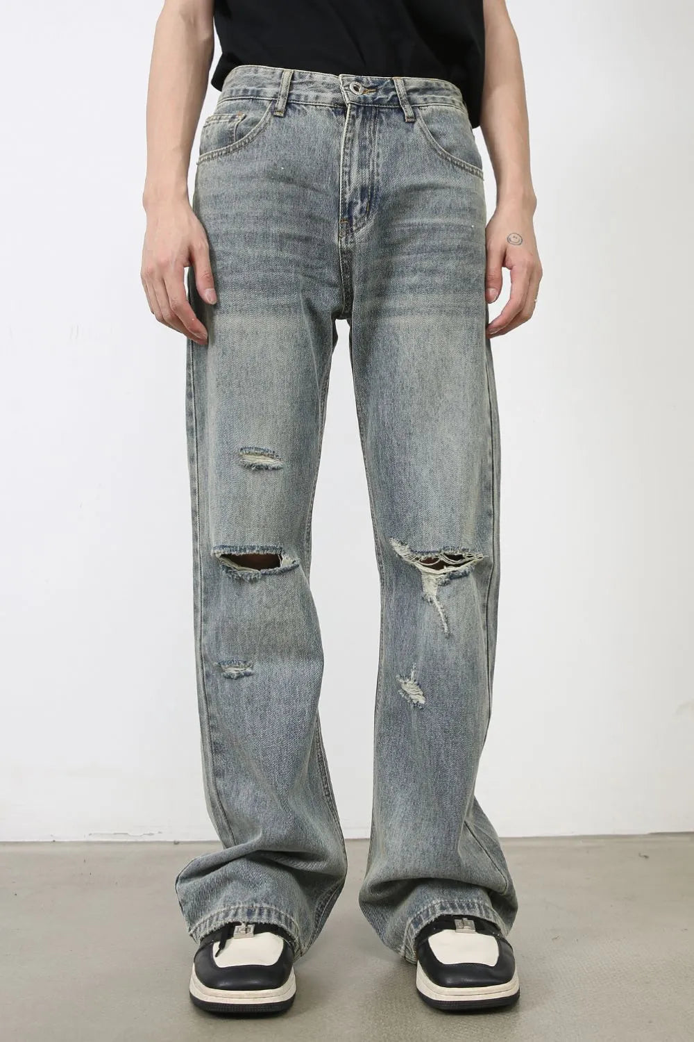 Distressed flare jeans in medium wash denim with raw-cut knee details and a relaxed fit.
