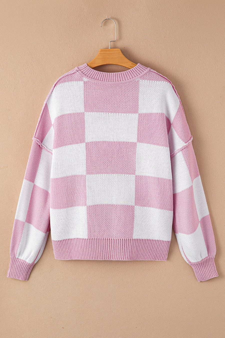 Checkerboard knit crewneck sweater in pink and white with balloon sleeves.