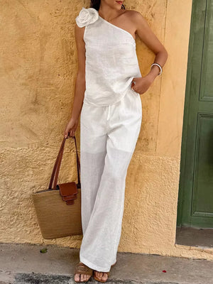 White cotton one-shoulder top with floral embellishment and wide-leg pants ensemble.