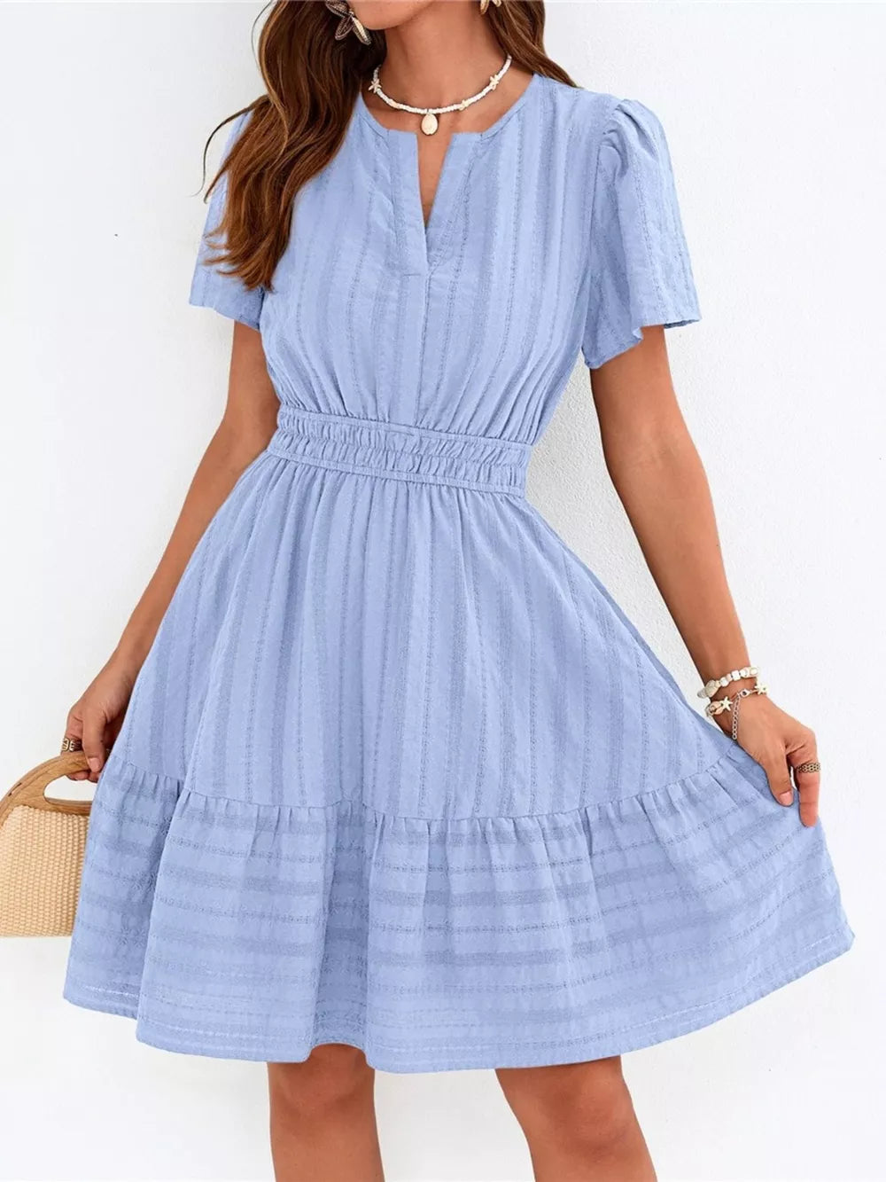 Light blue textured V-neck tiered dress with smocked waist and short sleeves.