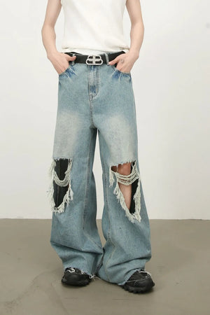 Distressed wide-leg denim jeans in medium wash with fraying and ripped knees.