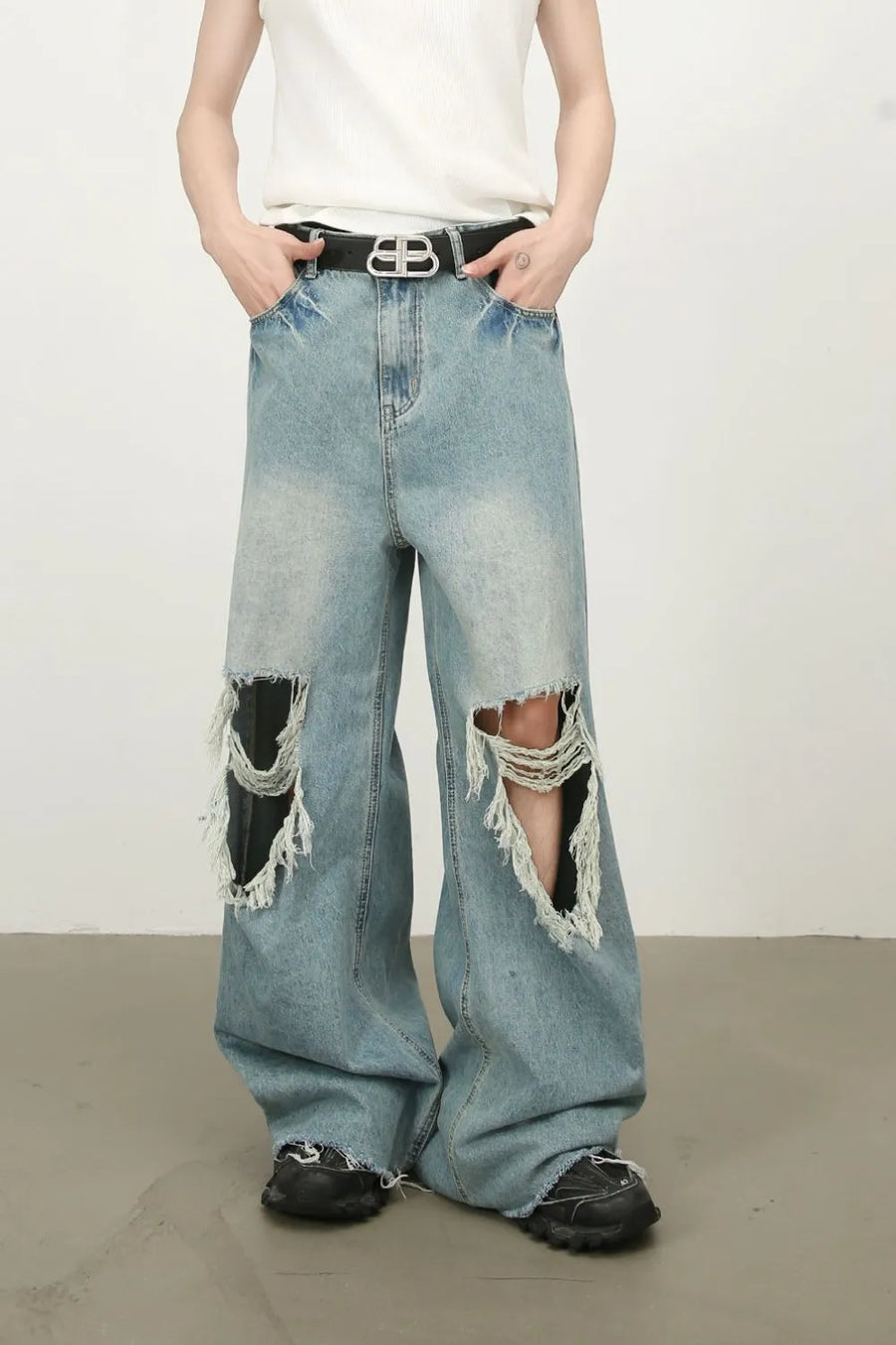 Distressed wide-leg denim jeans in medium wash with fraying and ripped knees.
