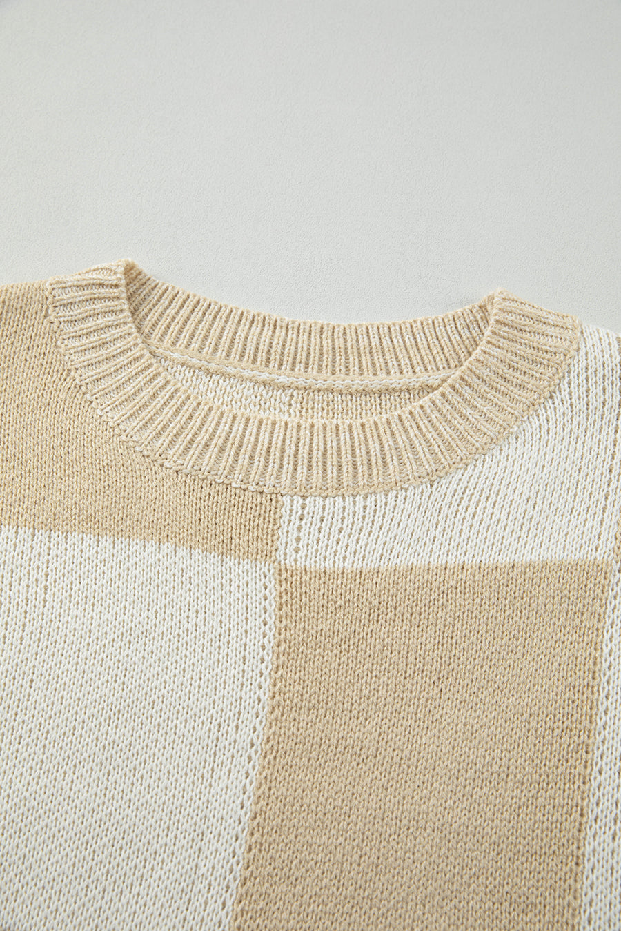 Beige and cream colorblock checkerboard knit sweater with crew neck.