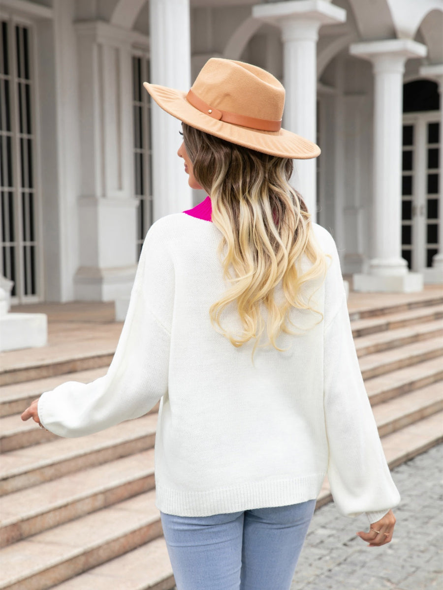 White acrylic sweater with a bright pink neckline detail, long sleeves, and relaxed fit.