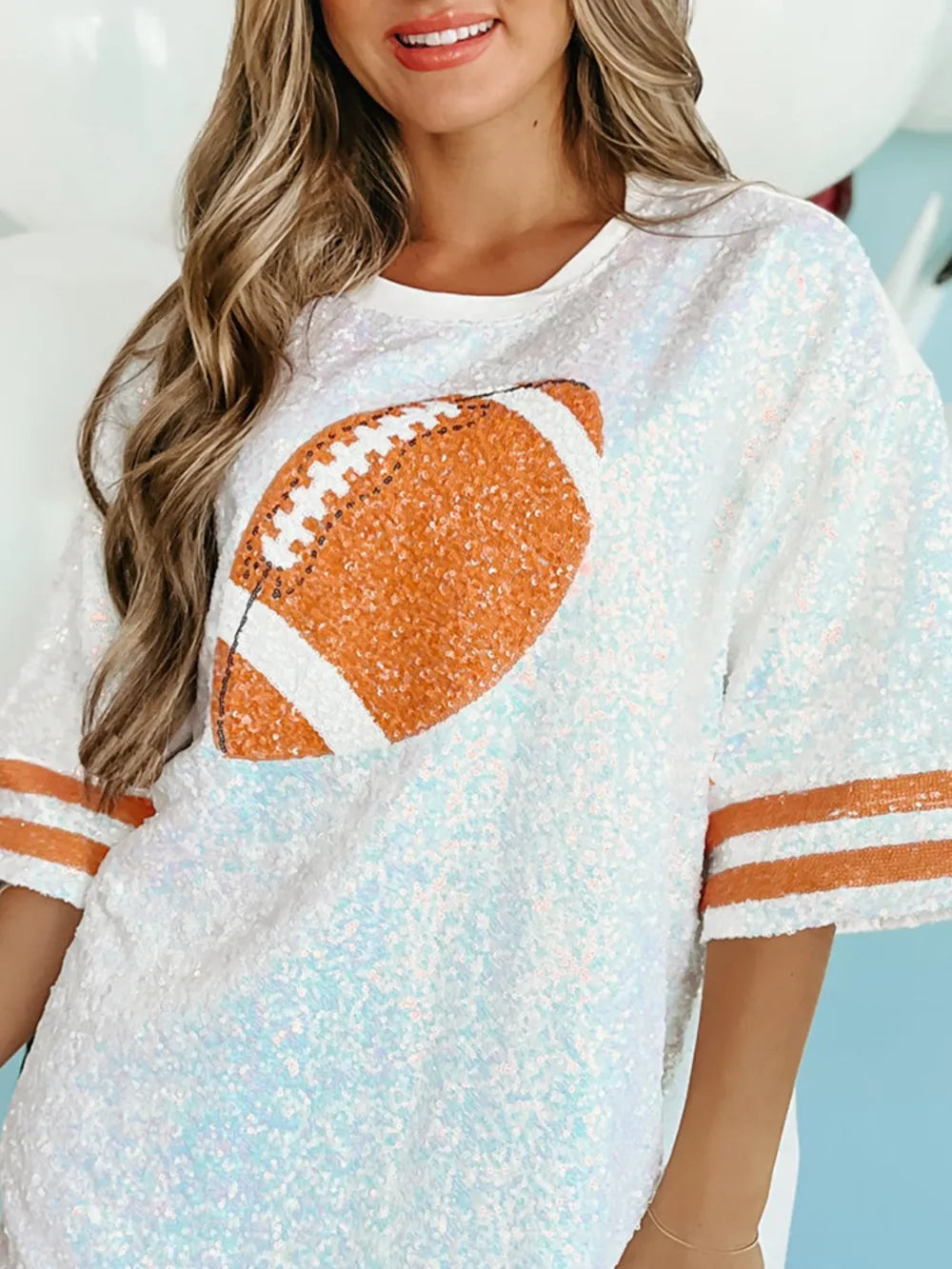 White sequin oversized tee dress with football graphic and orange striped sleeves.