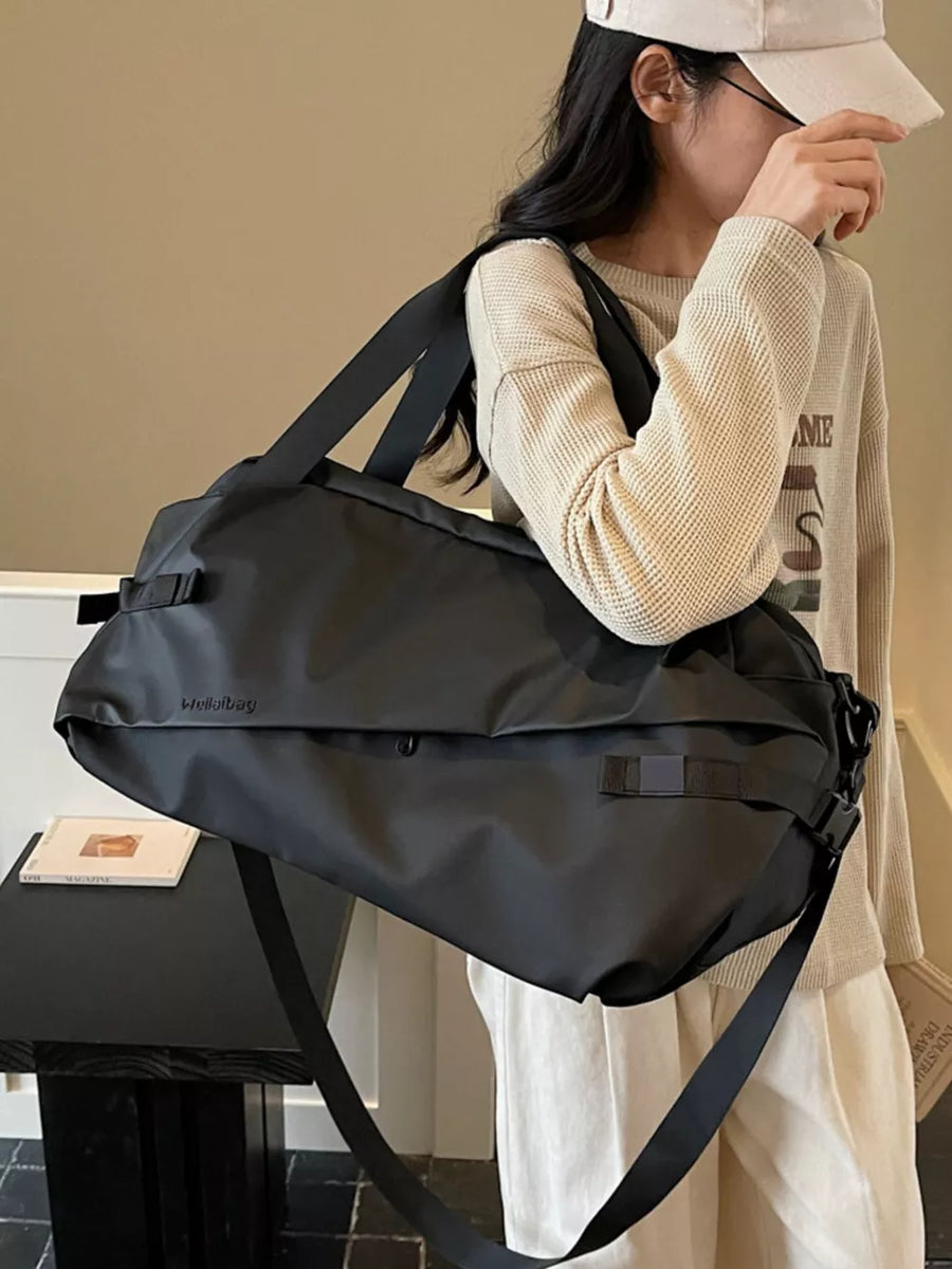 Black Oxford cloth travel bag with adjustable strap and buckle details