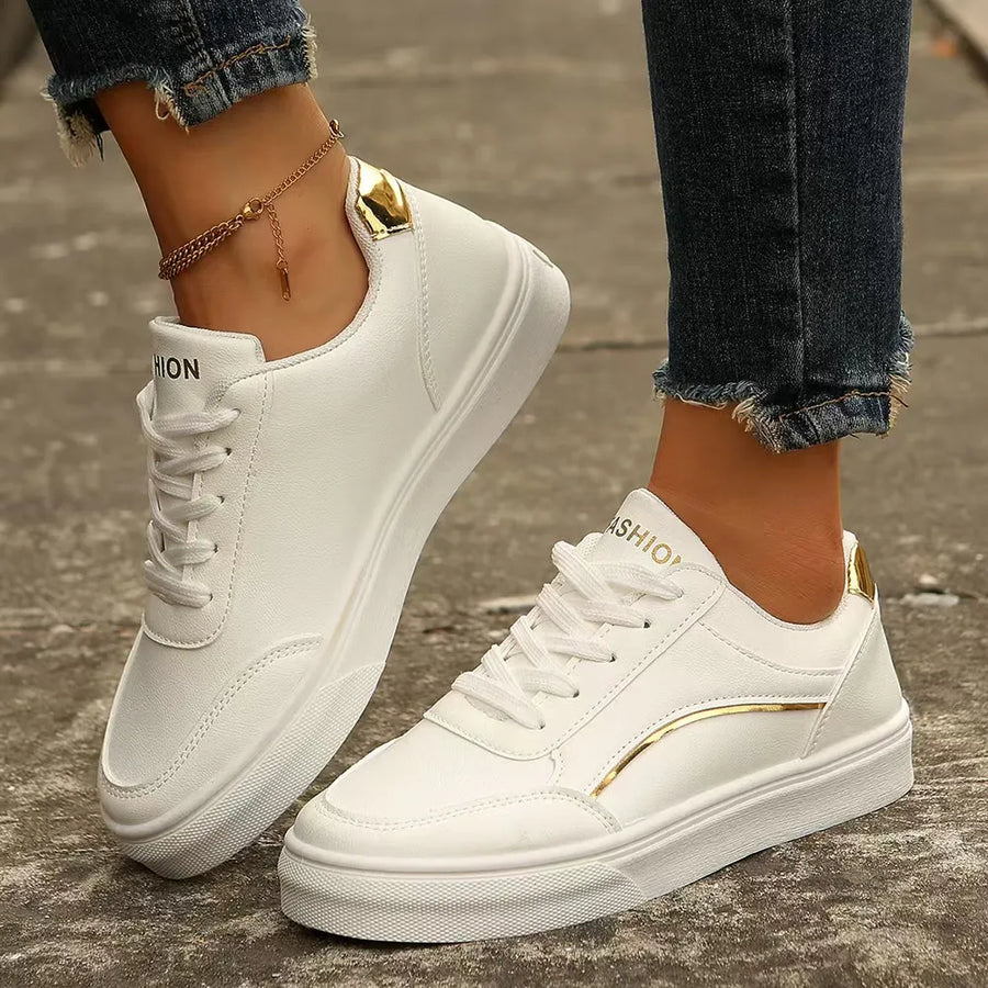 White sneakers with gold metallic trim and accents.