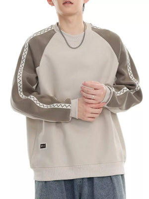 Oversized sweatshirt in beige with gray raglan sleeves featuring white zigzag stitching detail.
