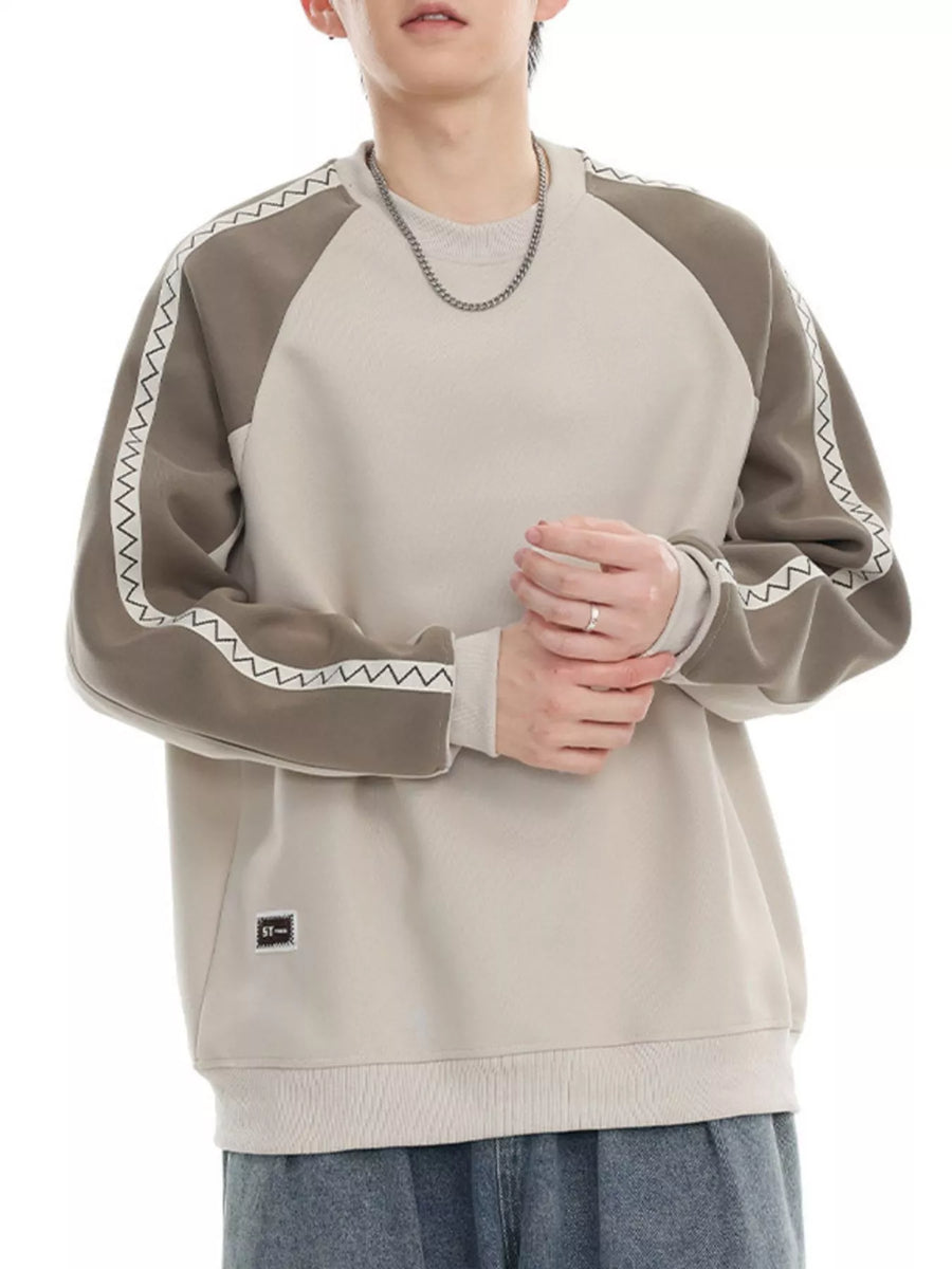 Oversized sweatshirt in beige with gray raglan sleeves featuring white zigzag stitching detail.