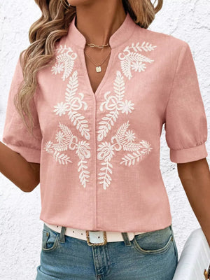 Pink embroidered blouse with cuffed sleeves and notched neckline.