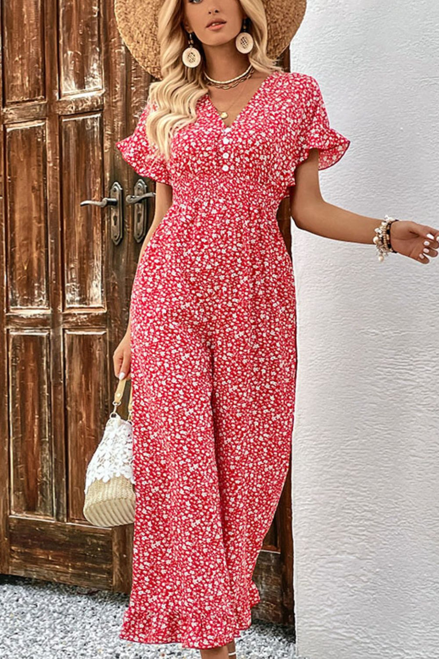 Smocked bodice floral jumpsuit with decorative buttons and flutter sleeves.