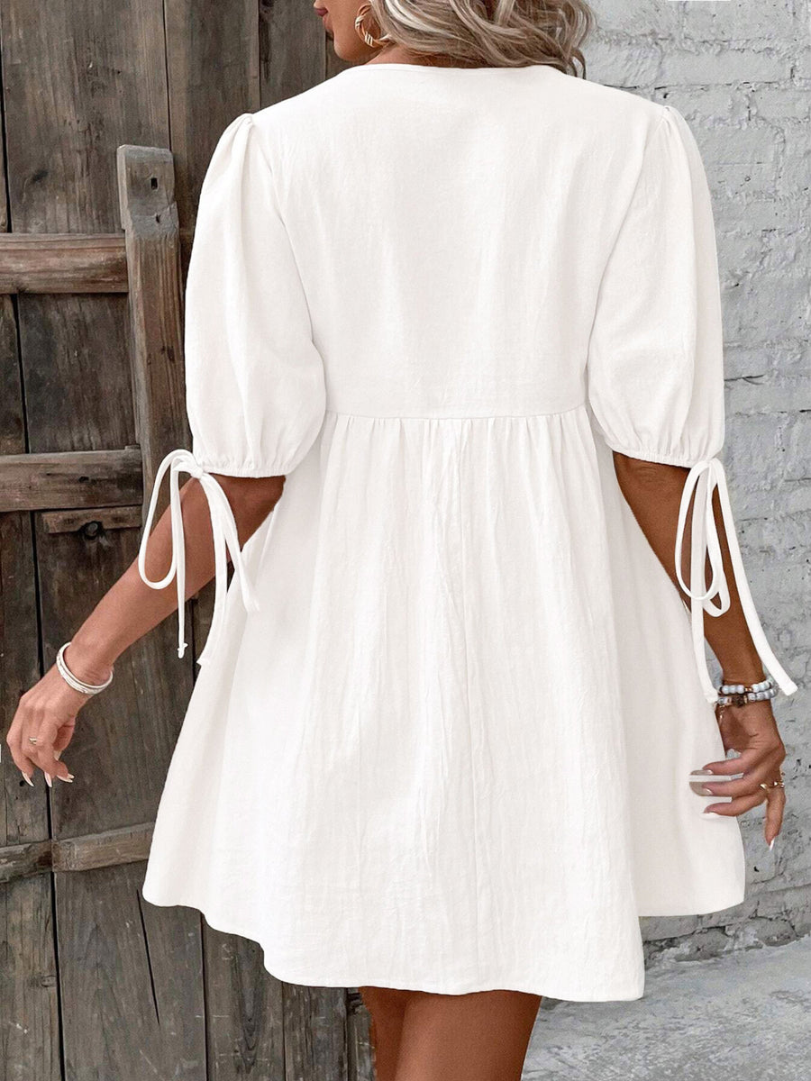 White tie front puff sleeve mini dress with adjustable tie cuffs and A-line skirt.