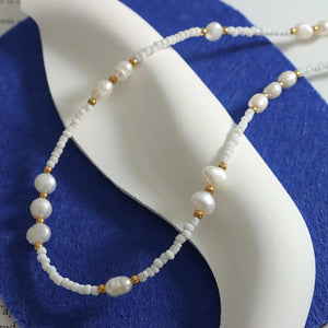White pearl and seed bead strand necklace with gold accents