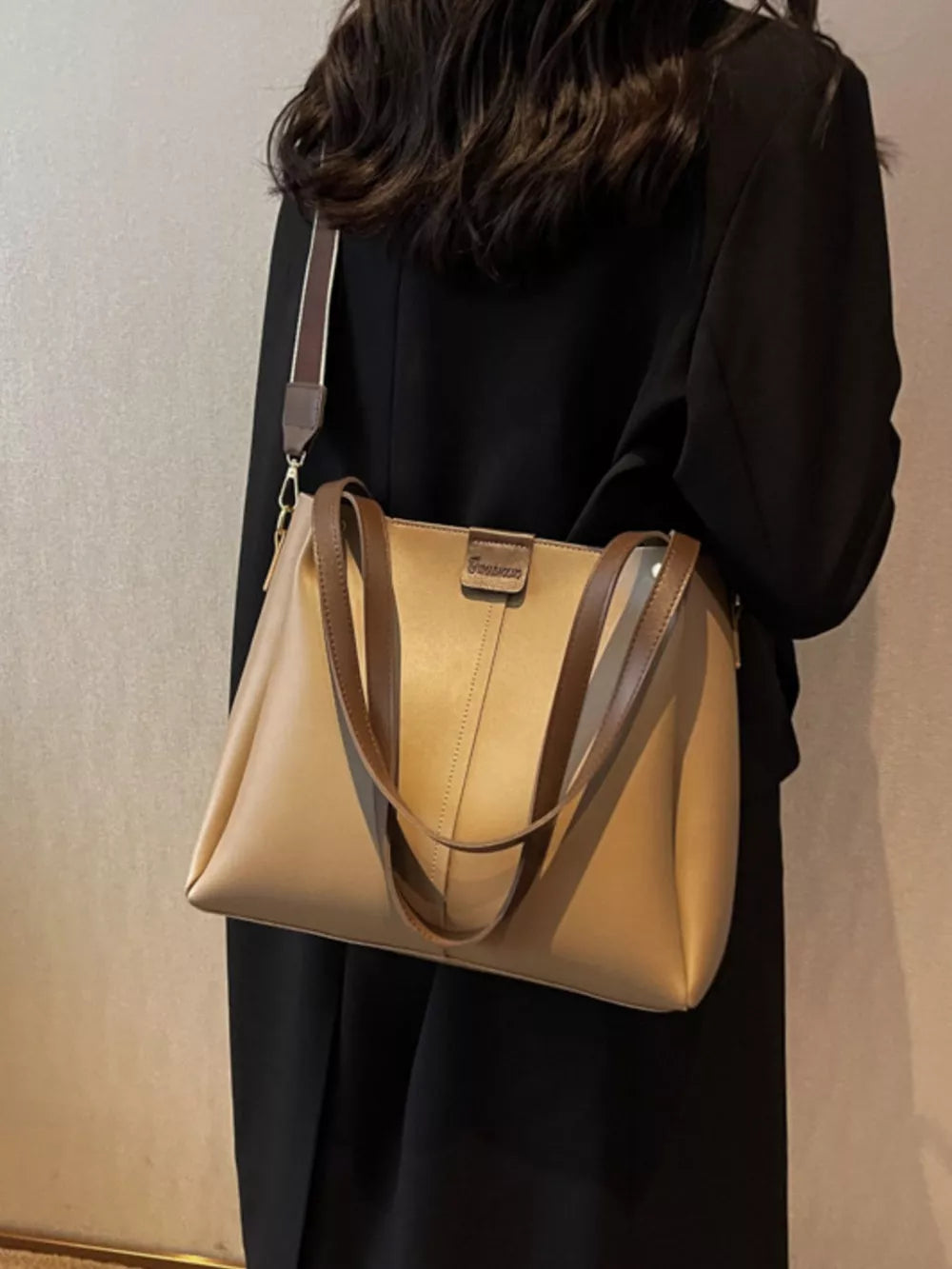 Khaki trapezoid pu leather bag with wide strap and brown handles.