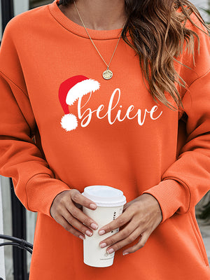 Orange Christmas graphic tunic sweatshirt with "Believe" text and Santa hat graphic.